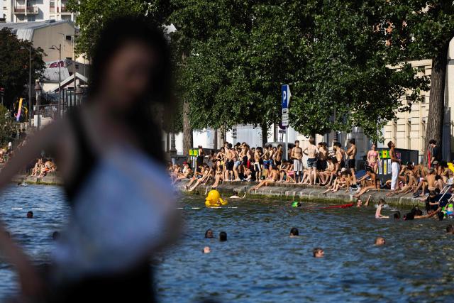 Swimmers sunbath on the banks of the Canal Saint-Martin as France experiences a heatwave, in Paris on June 22, 2026. Due to the ongoing heatwave sweeping across France - the Bassin des Recollets - a portion of the Canal Saint-Martin in the French capital has been opened for swimming from June 17. (Photo by JOEL SAGET / AFP)