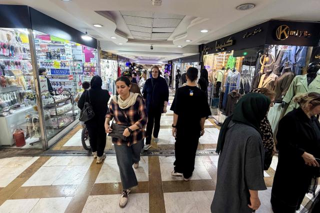 People walk at a mall in the Iranian capital Tehran on June 22, 2026. The United States temporarily suspended sanctions on Iranian oil on June 22 after Vice President JD Vance said Iran would allow UN nuclear inspectors to return to the country, following talks in Switzerland. (Photo by ATTA KENARE / AFP) / 