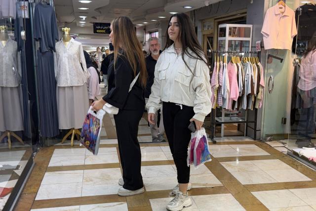 Women walk at a mall in the Iranian capital Tehran on June 22, 2026. The United States temporarily suspended sanctions on Iranian oil on June 22 after Vice President JD Vance said Iran would allow UN nuclear inspectors to return to the country, following talks in Switzerland. (Photo by ATTA KENARE / AFP) / 