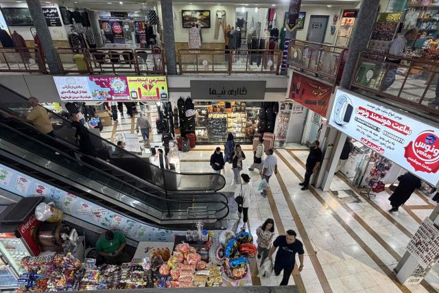 People walk at a mall in the Iranian capital Tehran on June 22, 2026. The United States temporarily suspended sanctions on Iranian oil on June 22 after Vice President JD Vance said Iran would allow UN nuclear inspectors to return to the country, following talks in Switzerland. (Photo by ATTA KENARE / AFP) / 