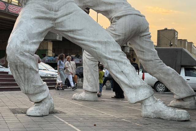 People walk past a pair of statues in Tehran on June 22, 2026. The United States temporarily suspended sanctions on Iranian oil on June 22 after Vice President JD Vance said Iran would allow UN nuclear inspectors to return to the country, following talks in Switzerland. (Photo by ATTA KENARE / AFP) / 