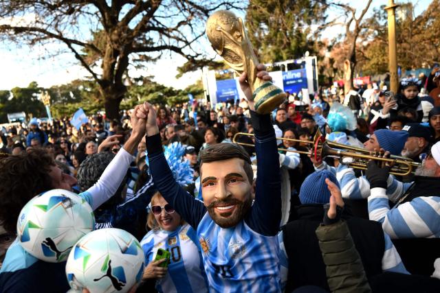 An Argentina fan wearing a mask of Argentine forward Lionel Messi celebrates while raising a replica of the FIFA World Cup trophy following the 2026 FIFA World Cup football match between Argentina and Austria in Buenos Aires on June 22, 2026. (Photo by Luis ROBAYO / AFP)