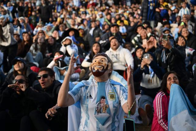 An Argentina fan wearing a mask depicting Argentine forward Lionel Messi reacts as she watches the 2026 FIFA World Cup Group J football match between Argentina and Austria on a giant screen in Buenos Aires on June 22, 2026. (Photo by Luis ROBAYO / AFP)