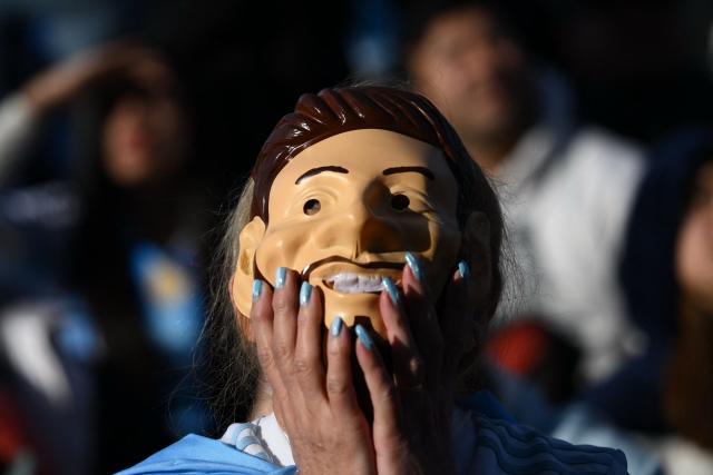An Argentina fan wearing a mask depicting Argentine forward Lionel Messi reacts as she watches the 2026 FIFA World Cup Group J football match between Argentina and Austria on a giant screen in Buenos Aires on June 22, 2026. (Photo by Luis ROBAYO / AFP)