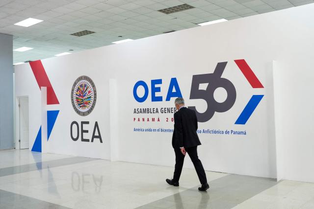 A man walks past a banner of the Organization of American States (OAS) during the 56th General Assembly of the OAS in Panama City on June 22, 2026. Panama is hosting the OAS General Assembly from June 24 to 26, bringing together foreign ministers, diplomats and representatives from across the Americas to discuss regional cooperation and key hemispheric issues. (Photo by ARNULFO FRANCO / AFP)