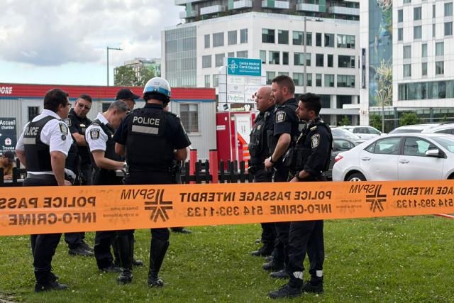 Damaged windows can be seen in the distance (top C) as police gather near the scene of a shooting in Montreal on June 22, 2026, which left three people dead. A midday shooting in Montreal killed three people on Monday, including a police officer, a civilian, and the alleged gunman, triggering rare alarm in the Canadian city. The bloodshed occurred in a partly Jewish neighborhood that includes kosher markets and restaurants, but police declined to comment on what the motive might have been and whether the incident amounted to a hate crime or act of terror. (Photo by Daphné LEMELIN / AFP)