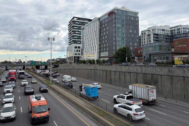 Cars drive on Decarie highway near the scene of a shooting (tall building at L) in Montreal on June 22, 2026, which left three people dead. A shooting Monday in a Jewish neighborhood of Montreal left three people dead, including a police officer, a resident and the alleged assailant, police in the Canadian city said. There was no immediate word on the motive of the attack in an area that has kosher restaurants and supermarkets frequented by Montreal's large Jewish community. (Photo by Daphné LEMELIN / AFP)
