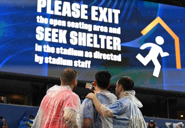 Fans take a selfie in front of a screen showing an evacuation warning during the 2026 World Cup Group I football match between France and Iraq at the Philadelphia Stadium in Philadelphia on June 22, 2026.  (Photo by ROBERTO SCHMIDT / AFP)
