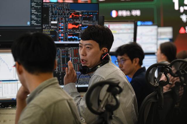 Currency dealers monitor exchange rates in a foreign exchange dealing room at the Hana Bank headquarters in Seoul on June 23, 2026. (Photo by Jade GAO / AFP)