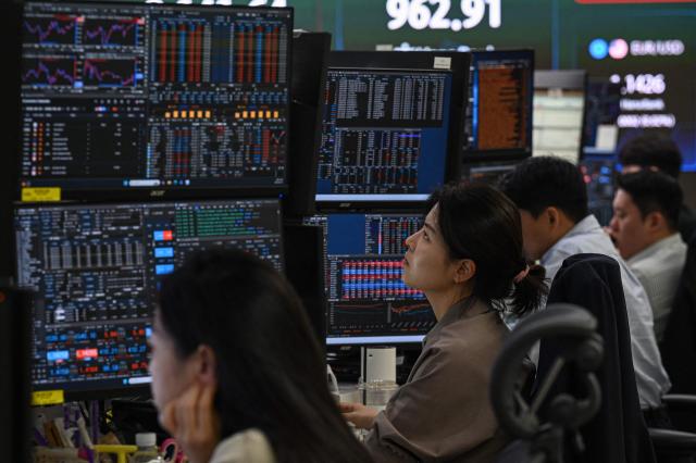 Currency dealers monitor exchange rates in a foreign exchange dealing room at the Hana Bank headquarters in Seoul on June 23, 2026. (Photo by Jade GAO / AFP)