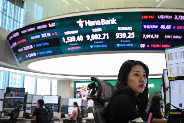 Currency dealers monitor exchange rates as an electronic screen (top) shows South Korea's benchmark stock index (KOSPI) in a foreign exchange dealing room at the Hana Bank headquarters in Seoul on June 23, 2026. (Photo by Jade GAO / AFP)
