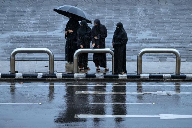 Burqa-clad women wait for a taxi amid rainfall in Mumbai on June 23, 2026. (Photo by Punit PARANJPE / AFP)