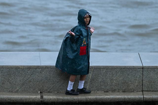 A child enjoys during rainfall while going to school, in Mumbai on June 23, 2026. (Photo by Punit PARANJPE / AFP)