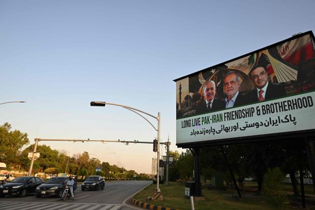Commuters ride past an electronic board featuring Iran's President Masoud Pezeshkian (C), Pakistan's Prime Minister Shehbaz Sharif (L) and President Asif Ali Zardari (R), displayed along a road in Islamabad on June 22, 2026 on the eve of Pezeshkian's visit to Pakistan amid US-Iran peace talks. Iranian President Masoud Pezeshkian will travel to Pakistan on June 23, state media reported, following talks between Tehran and Washington in Switzerland which were mediated by Islamabad. (Photo by Aamir QURESHI / AFP)
