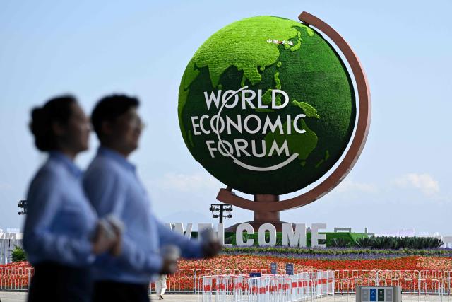 A flower installation and globe with the logo of the World Economic Forum is pictured outside the Dalian International Conference Centre during the World Economic Forum Annual Meeting of the New Champions in Dalian, China's Liaoning province, on June 23, 2026. (Photo by WANG Zhao / AFP)