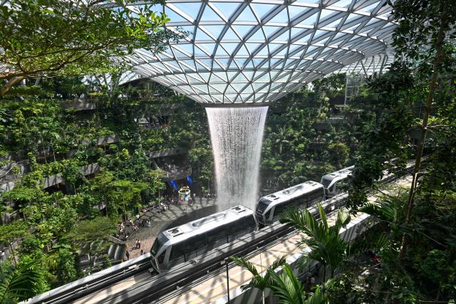 A monorail train travels through the Jewel Complex next to the Rain Vortex, the world's tallest indoor waterfall, at Singapore Changi Airport in Singapore on June 23, 2026. (Photo by Roslan RAHMAN / AFP)