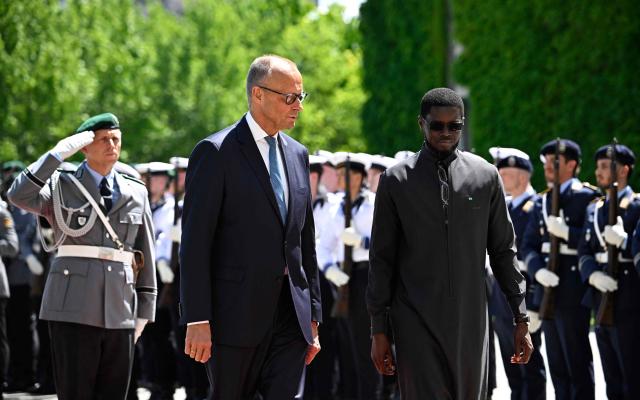 German Chancellor Friedrich Merz (2nd R) and Senegal's President Bassirou Diomaye Faye (R) review a military honor guard during a welcome ceremony at the Chancellery in Berlin on June 23, 2026. (Photo by Tobias SCHWARZ / AFP)