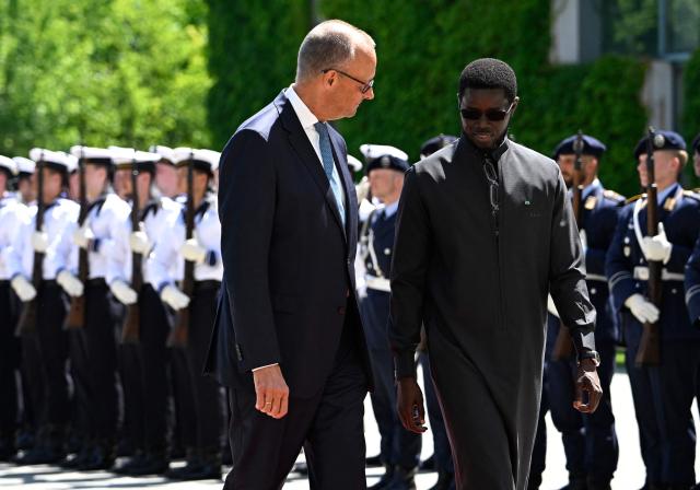 German Chancellor Friedrich Merz (L) and Senegal's President Bassirou Diomaye Faye review a military honor guard during a welcome ceremony at the Chancellery in Berlin on June 23, 2026. (Photo by Tobias SCHWARZ / AFP)