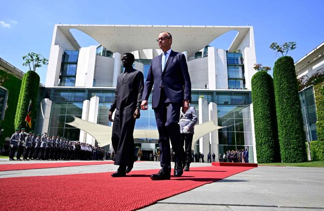 German Chancellor Friedrich Merz (R) and Senegal's President Bassirou Diomaye Faye review a military honor guard during a welcome ceremony at the Chancellery in Berlin on June 23, 2026. (Photo by Tobias SCHWARZ / AFP)