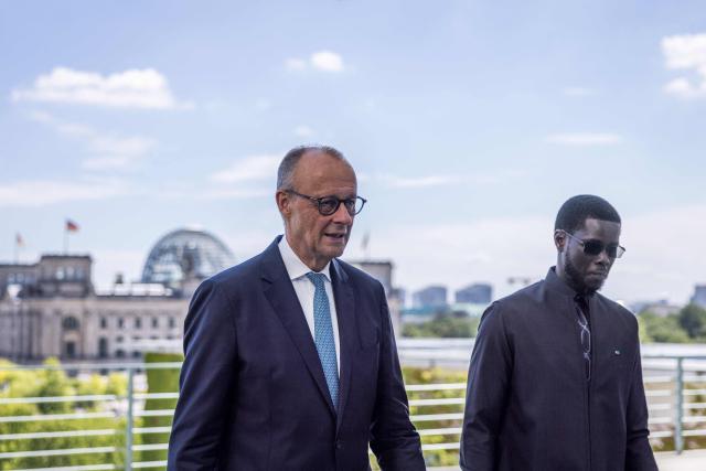 German Chancellor Friedrich Merz (L) and Senegal's President Bassirou Diomaye Faye stand on a balcony of the Chancellery as in background can be seen the Reichstag building that houses the Bundestag (lower house of parliament) in Berlin on June 23, 2026. (Photo by Nadja Wohlleben / POOL / AFP)