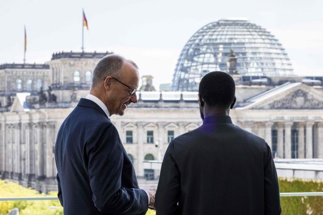 German Chancellor Friedrich Merz (L) and Senegal's President Bassirou Diomaye Faye stand on a balcony of the Chancellery and look towards the Reichstag building that houses the Bundestag (lower house of parliament) in Berlin on June 23, 2026. (Photo by Nadja Wohlleben / POOL / AFP)