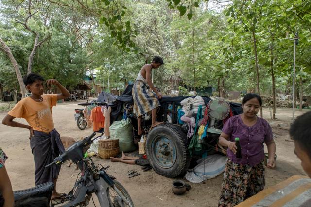 This photo taken on June 21, 2026 shows people, displaced by fighting between Myanmar's military and the People's Defence Forces (PDF) in Myit Chay, standing next to a shelter near Pakokku in Myanmar's Magway region. (Photo by AFP)