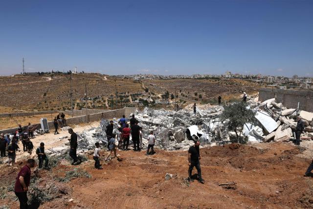 Palestinians stand on the flattened home of the al-Atrash family, after it was destroyed by Israel citing the lack of a building permit, in the village of Qilqes, a few kilometres from the Israeli settlement of Beit Hagai, just south of the Israeli-occupied West Bank city of Hebron on June 23, 2026. Excluding east Jerusalem, which was occupied and annexed by Israel in 1967, some 500,000 Israeli settlers live in the West Bank, along with about three million Palestinian residents. (Photo by HAZEM BADER / AFP) / 