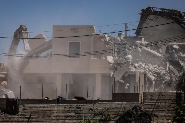 Israeli bulldozers guarded by Israeli soldiers demolish the home belonging to the Palestinian al-Atrash family, citing the lack of a building permit, in the village of Qilqes, a few kilometres from the Israeli settlement of Beit Hagai, just south of the Israeli-occupied West Bank city of Hebron on June 23, 2026. Excluding east Jerusalem, which was occupied and annexed by Israel in 1967, some 500,000 Israeli settlers live in the West Bank, along with about three million Palestinian residents. (Photo by HAZEM BADER / AFP) / 