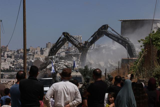 Israeli bulldozers guarded by Israeli soldiers demolish the home and shops belonging to the Palestinian al-Atrash family, citing the lack of a building permit, in the village of Qilqes, a few kilometres from the Israeli settlement of Beit Hagai, just south of the Israeli-occupied West Bank city of Hebron on June 23, 2026. Excluding east Jerusalem, which was occupied and annexed by Israel in 1967, some 500,000 Israeli settlers live in the West Bank, along with about three million Palestinian residents. (Photo by HAZEM BADER / AFP) / 