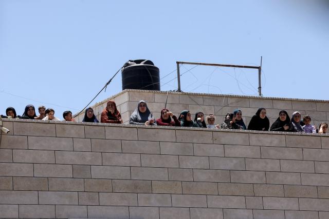 Palestinians stand on the roof of a nearby home as they watch Israeli bulldozers under the guard of soldiers demolish the home and shops belonging to the Palestinian al-Atrash family, citing the lack of a building permit, in the village of Qilqes, a few kilometres from the Israeli settlement of Beit Hagai, just south of the Israeli-occupied West Bank city of Hebron on June 23, 2026. Excluding east Jerusalem, which was occupied and annexed by Israel in 1967, some 500,000 Israeli settlers live in the West Bank, along with about three million Palestinian residents. (Photo by HAZEM BADER / AFP) / 