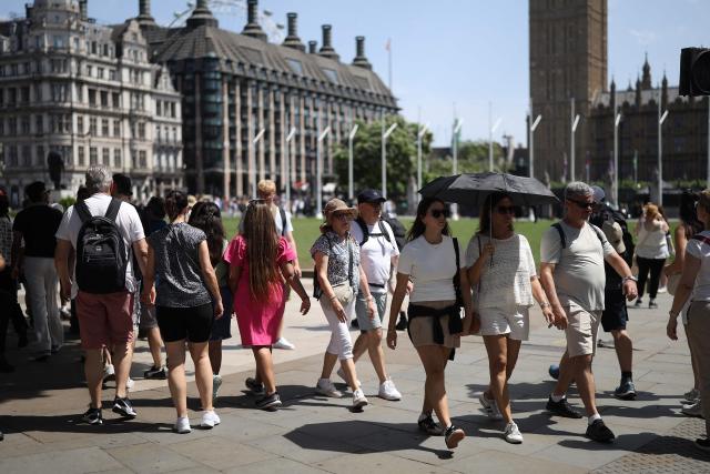 A person uses an umbrella to shelter from the direct sun,  on a hot summer's day, in London on June 23, 2026. (Photo by Toby Shepheard / AFP)