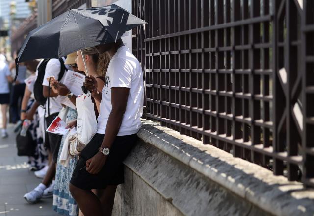 A person uses an umbrella to shelter from the direct sun, on a hot summer's day, in London on June 23, 2026. (Photo by Toby Shepheard / AFP)
