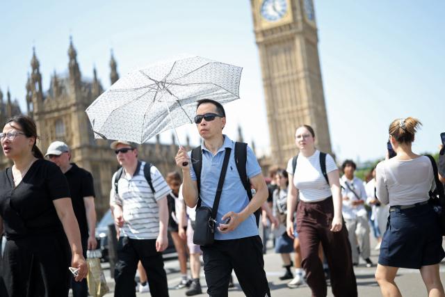 A person uses an umbrella to shelter from the direct sun,  on a hot summer's day, in London on June 23, 2026. (Photo by Toby Shepheard / AFP)