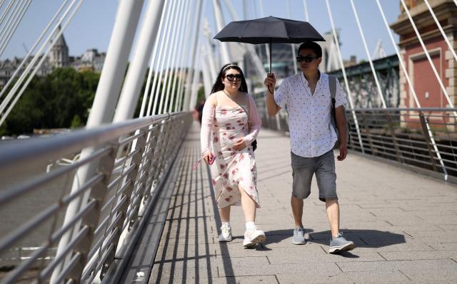 People use an umbrella to shelter from the direct sun, on a hot summer's day, in London on June 23, 2026. (Photo by Toby Shepheard / AFP)