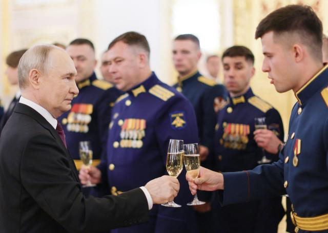 In this pool photograph distributed by the Russian state agency Sputnik, Russia's President Vladimir Putin toasts with graduates of higher military educational institutions during a meeting at the Kremlin in Moscow on June 23, 2026. (Photo by Gavriil Grigorov / POOL / AFP)