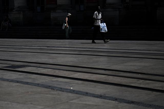 Pedestrians walk along tramway tracks in Bordeaux, southwestern France on June 23, 2026, as France experiences a heatwave. (Photo by Christophe ARCHAMBAULT / AFP)