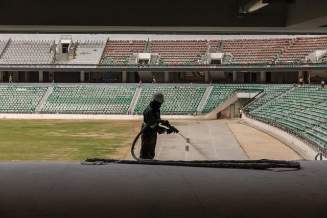A construction worker sprays plastic paint on seats at the Raila Odinga International Stadium, also known as Talanta Sports Stadium, a 60,000-seat national stadium under construction in Nairobi on June 23, 2026, ahead the Africa Cup of Nations (AFCON) scheduled for 2027. (Photo by SIMON MAINA / AFP)