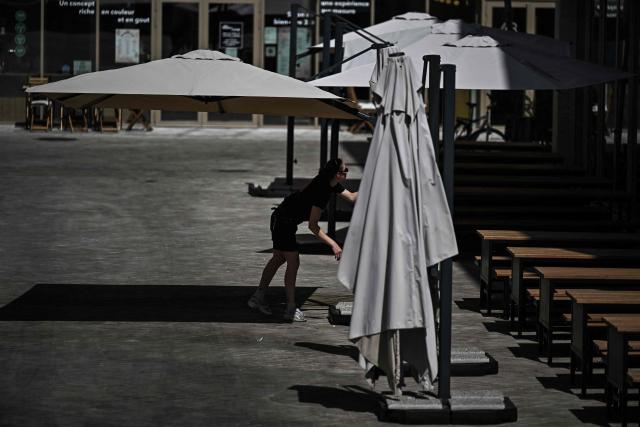 A employee opens sunshades at the terrasse of a cafe in Bordeaux, southwestern France on June 23, 2026, as France experiences a heatwave. (Photo by Christophe ARCHAMBAULT / AFP)