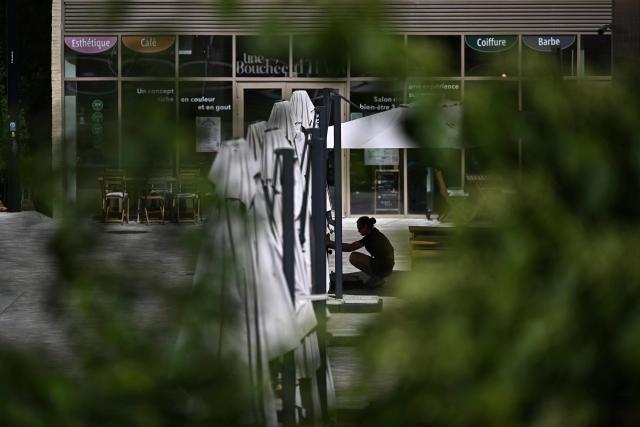 A employee opens sunshades at the terrasse of a cafe in Bordeaux, southwestern France on June 23, 2026, as France experiences a heatwave. (Photo by Christophe ARCHAMBAULT / AFP)