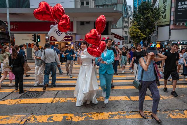A couple cross a street while taking pre-wedding photos in Hong Kong on June 23, 2026. (Photo by Dale DE LA REY / AFP)