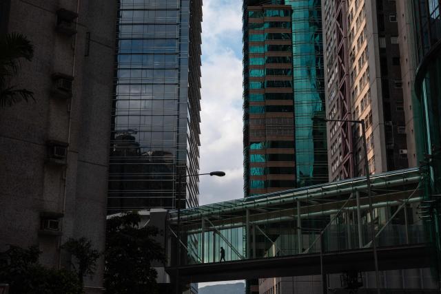 A man crosses a bridge between office towers in Hong Kong on June 23, 2026. (Photo by Dale DE LA REY / AFP)