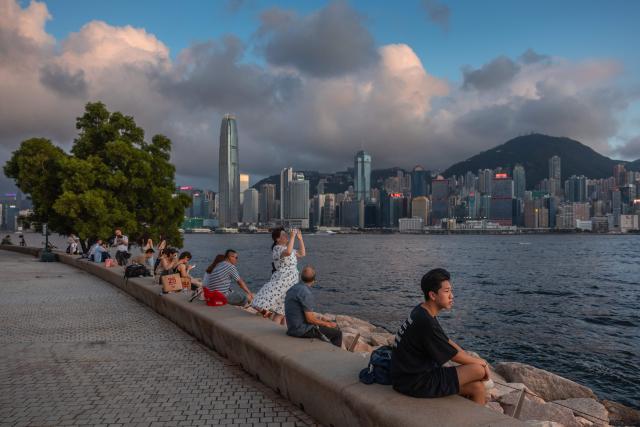 People sit on a promenade along Victoria Harbour in Hong Kong on June 23, 2026. (Photo by Dale DE LA REY / AFP)