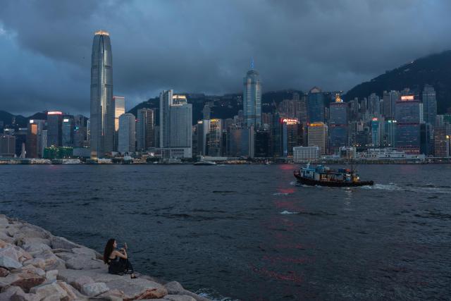 A woman sits on a promenade along Victoria Harbour in Hong Kong on June 23, 2026. (Photo by Dale DE LA REY / AFP)