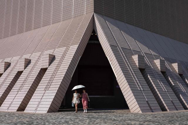 Women use an umbrella to block the sun while visiting a promenade along Victoria Harbour in Hong Kong on June 22, 2026. (Photo by Dale DE LA REY / AFP)