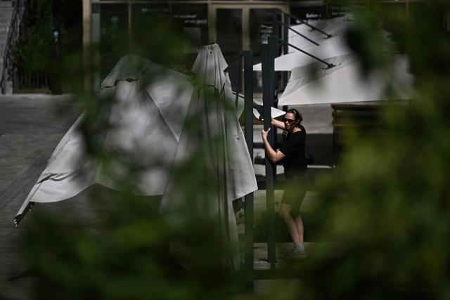 A employee opens sunshades at the terrasse of a cafe in Bordeaux, southwestern France on June 23, 2026, as France experiences a heatwave. (Photo by Christophe ARCHAMBAULT / AFP)