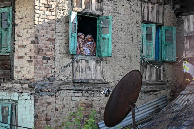 EDITORS NOTE: Graphic content / Kashmiri Muslim women watch from a window as Shia mourners attend a religious procession on the seventh day of Ashura during the Islamic holy month of Muharram in Srinagar on June 23, 2026. (Photo by Tauseef MUSTAFA / AFP)