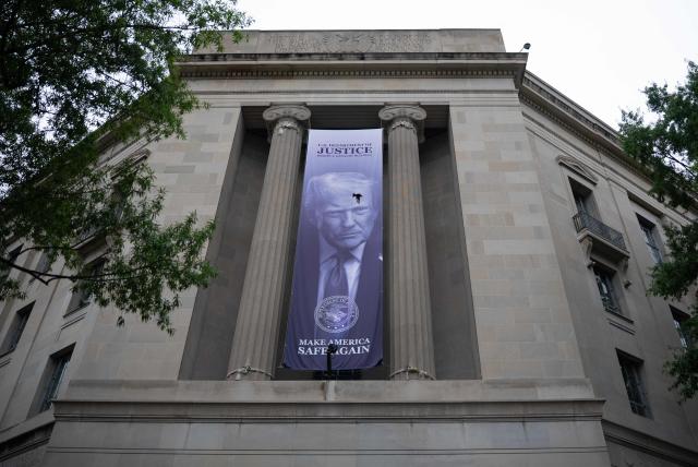 A banner featuring US President Donald Trump hangs on the outside of the Department of Justice headquarters ahead of a press conference with Acting Attorney General Todd Blanche announcing annual healthcare fraud takedown results in Washington, DC on June 23, 2026. (Photo by Ken Cedeno / AFP)