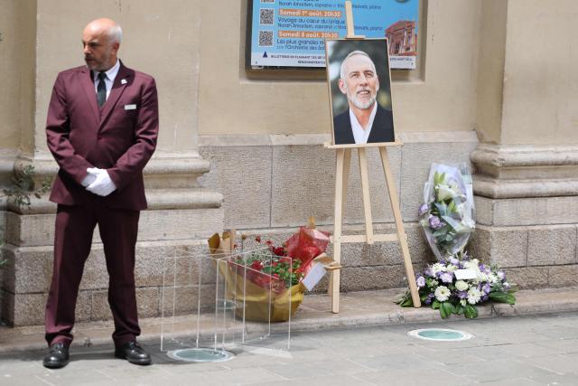 A funeral officer stands next to the portrait of Eric Roy displayed during a funeral ceremony outside the Cathédrale Sainte-Réparate in Nice, Southeastern France, on June 23, 2026. (Photo by Valery HACHE / AFP)