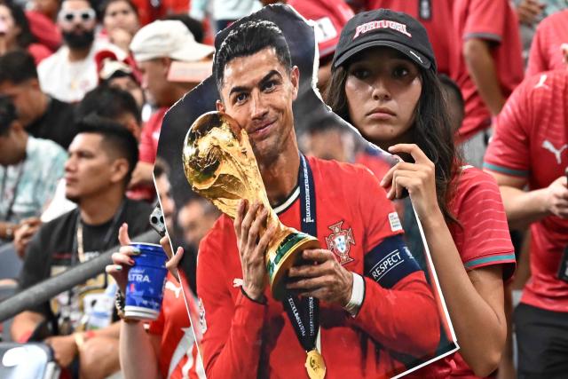 A Portugal supporter holds a cardboard sign featuring Cristiano Ronaldo holding the World Cup trophy ahead of the 2026 World Cup Group K football match between Portugal and Uzbekistan at the Houston Stadium in Houston on June 23, 2026.  (Photo by Paul ELLIS / AFP)