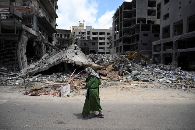 A woman walks past flattened building as workers remove the rubble from the site of an earlier Israeli military strike on a neighbourhood in the southern Lebanese coastal city of Tyre on June 23, 2026. On June 22, 2026, mediators Pakistan and Qatar said that Tehran and Washington had agreed to set up a "de-confliction cell" to limit flare-ups in Lebanon following talks in Switzerland on ending the wider Middle East war, which Tehran has linked to halting the parallel conflict in Lebanon. (Photo by Joseph EID / AFP) / 
